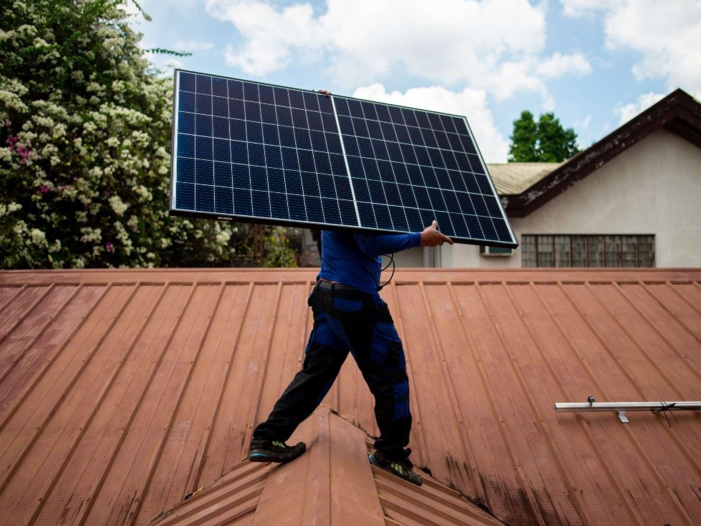 A worker from PHILERGY, a German-Filipino supplier and installer of solar energy, carries a solar panel during a home installation